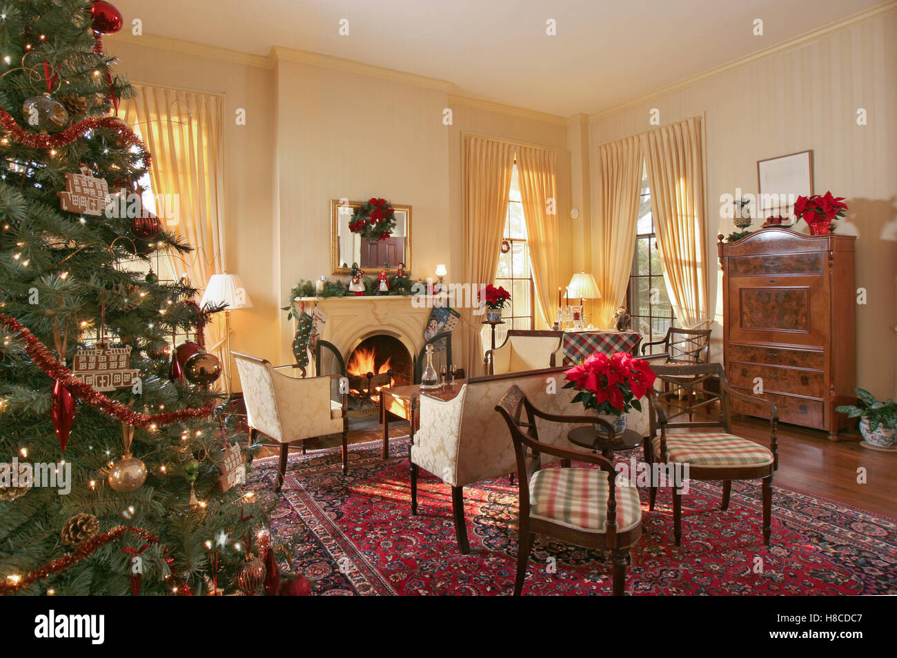 Upholstered chairs in front of fireplace with lit fire in sitting room decorated for Christmas