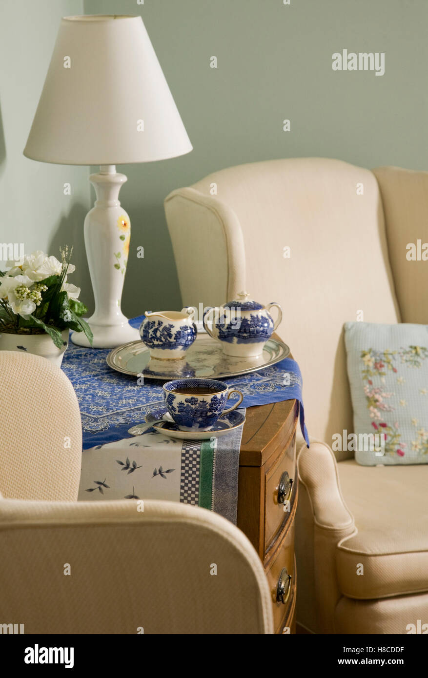 Tea set on chest of drawers between pair of upholstered armchairs Stock