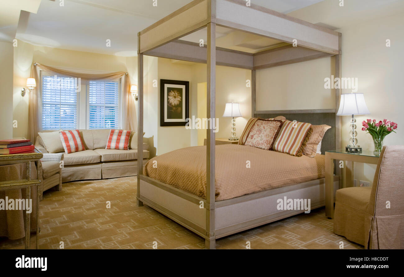 Upholstered four poster bed and sofa in contemporary bedroom Stock