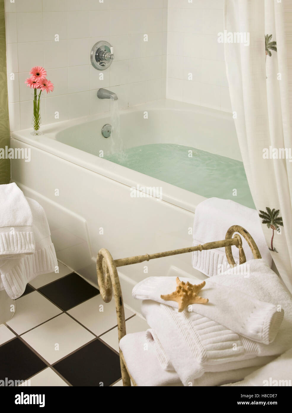 Water running from tap fitting into bathtub. Stock Photo