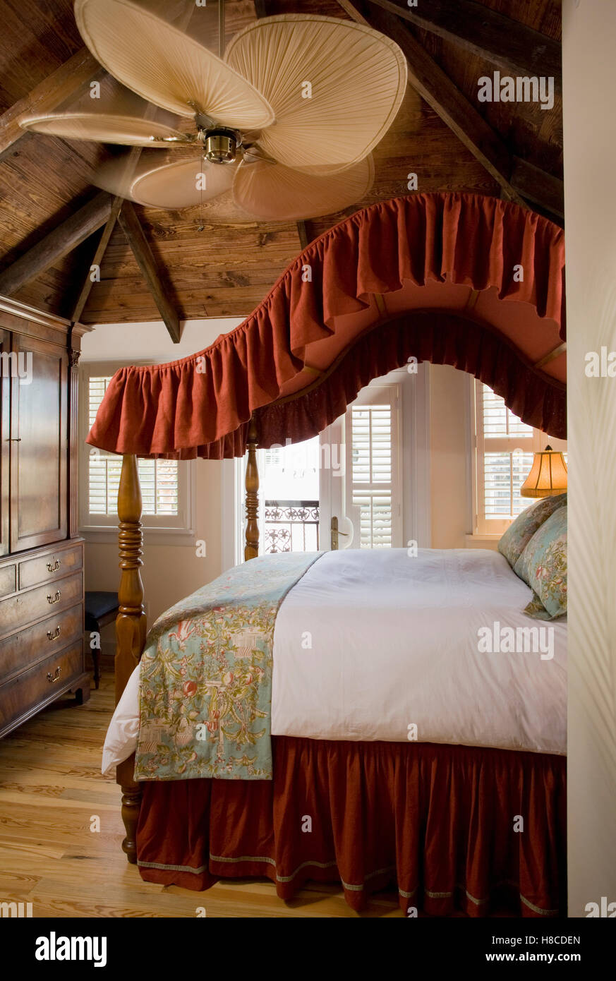 View Through Doorway To Wooden Four Poster Bed With Red Fabric