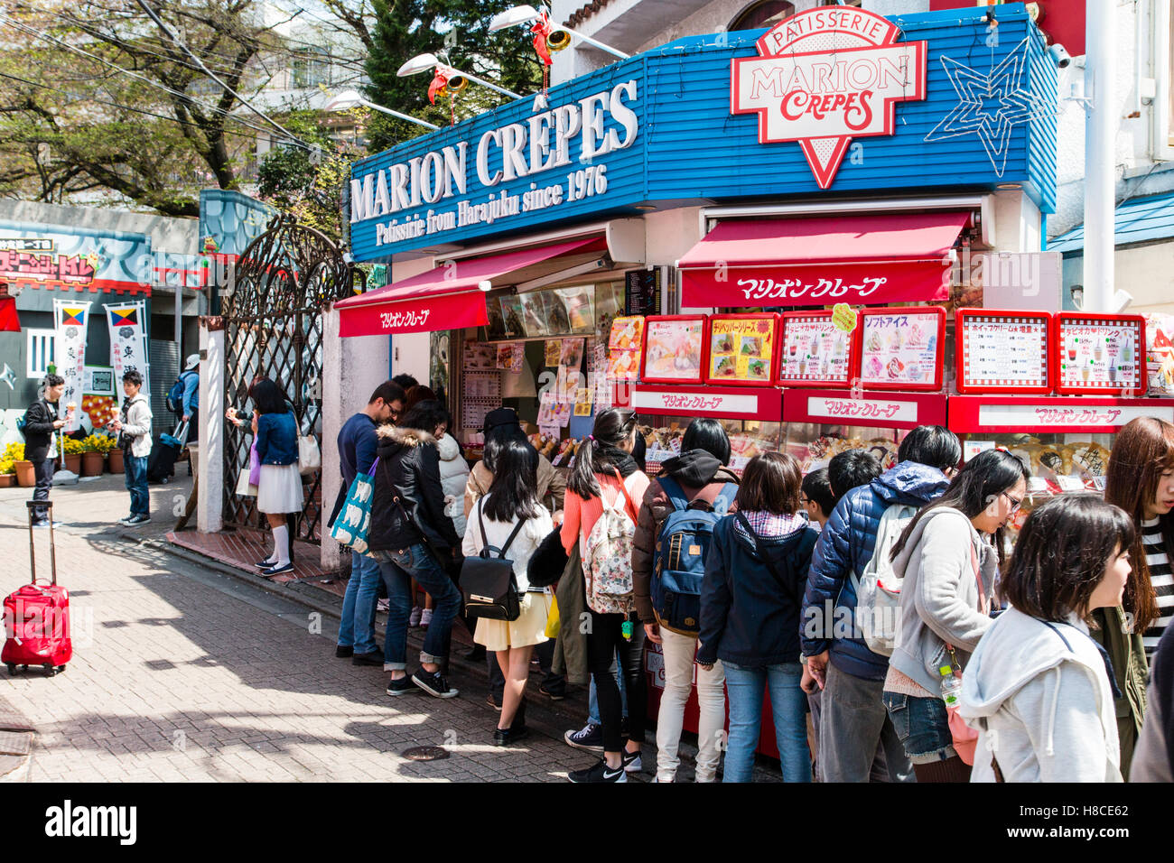 Japan, Tokyo, Harajuku, Takeshita-dori. Marion Crepes, famous patisserie with queue of Japanese teenagers queuing in winter sunshine. Stock Photo