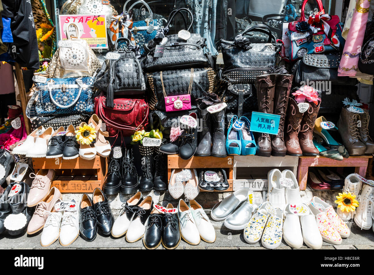 Japan, Tokyo, Harajuku, Takeshita-dori. Hand Bags, boots and shoes displayed on the pavement outside trendy teenage fashion store. Stock Photo