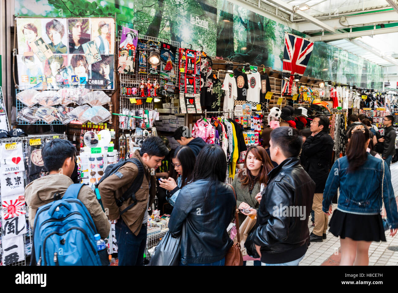 Japan, Tokyo, Harajuku, Takeshita dori. Street view, group of teenagers outside shop with outside display stands selling accessories, Union Jack hangs. Stock Photo