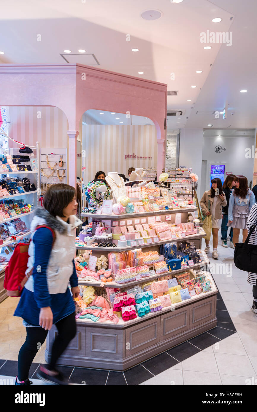 Japan, Tokyo, Harajuku. Takeshita dori. Interior of young girl and teenagers fashion accessory store. Young girl walking past a display counter. Stock Photo