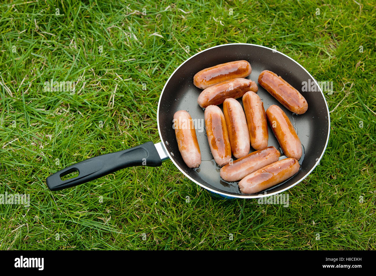 Sausages frying in a pan on a camping stove Stock Photo