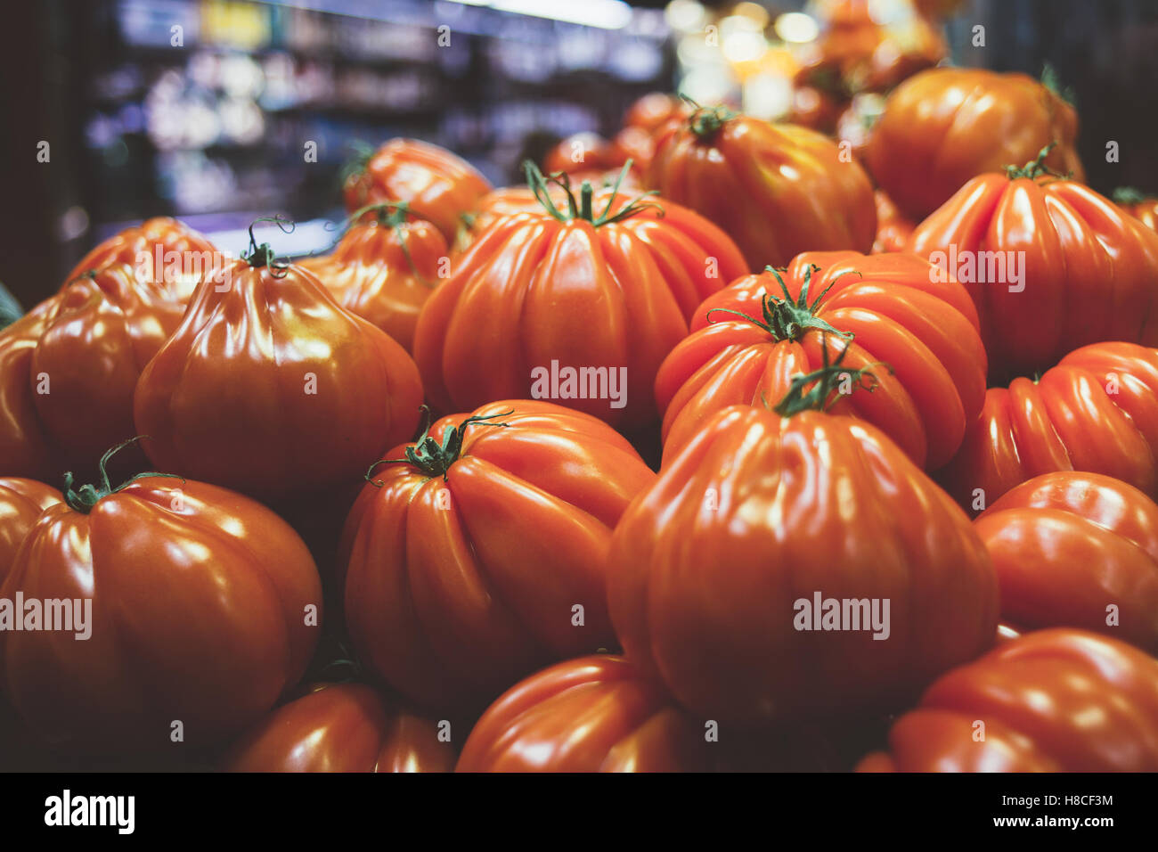 A bunch of tomatoes for sale at an indoor market. Stock Photo