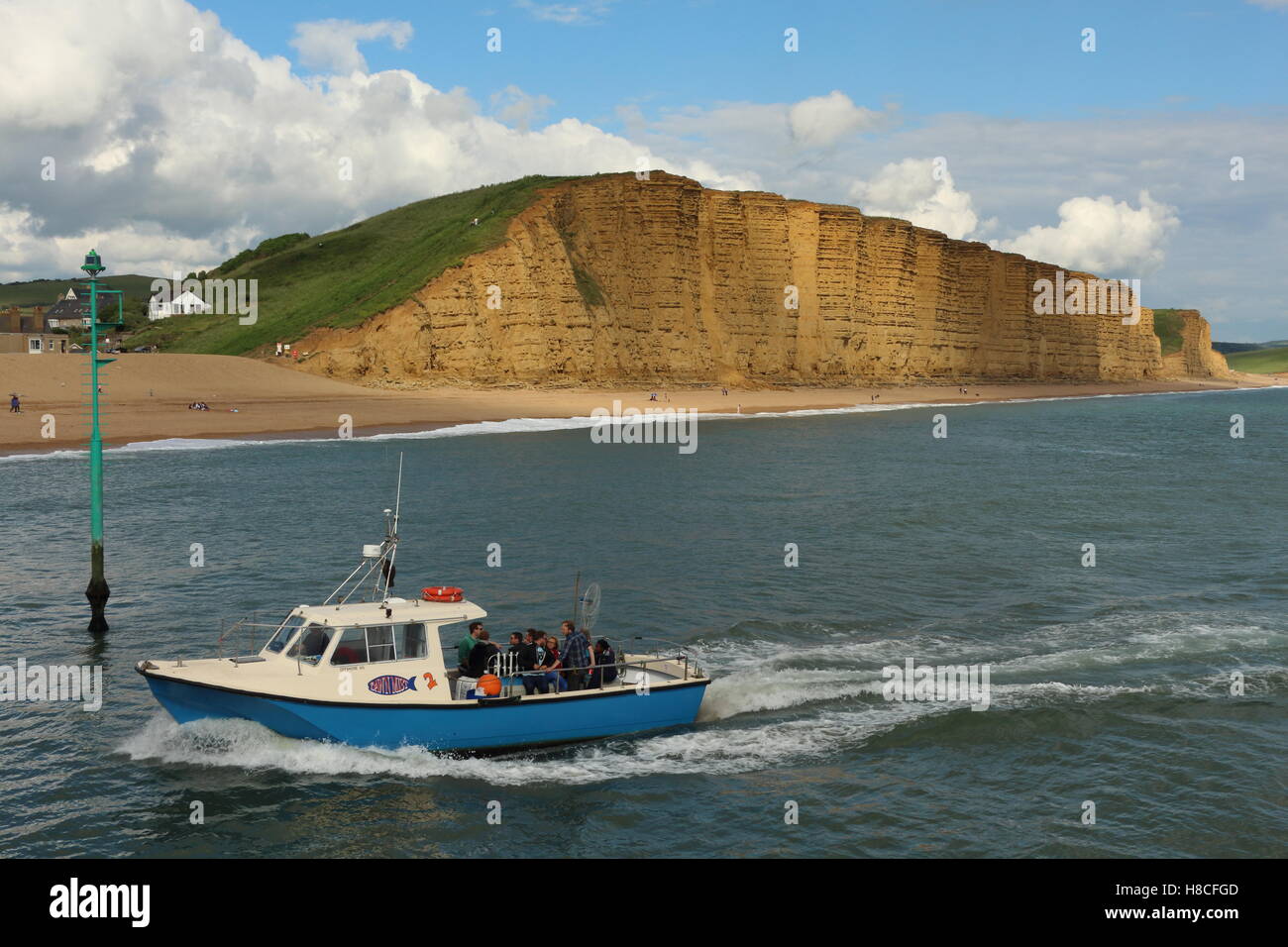 Small sea fishing boat returning to harbour at West Bay with the cliffs ...
