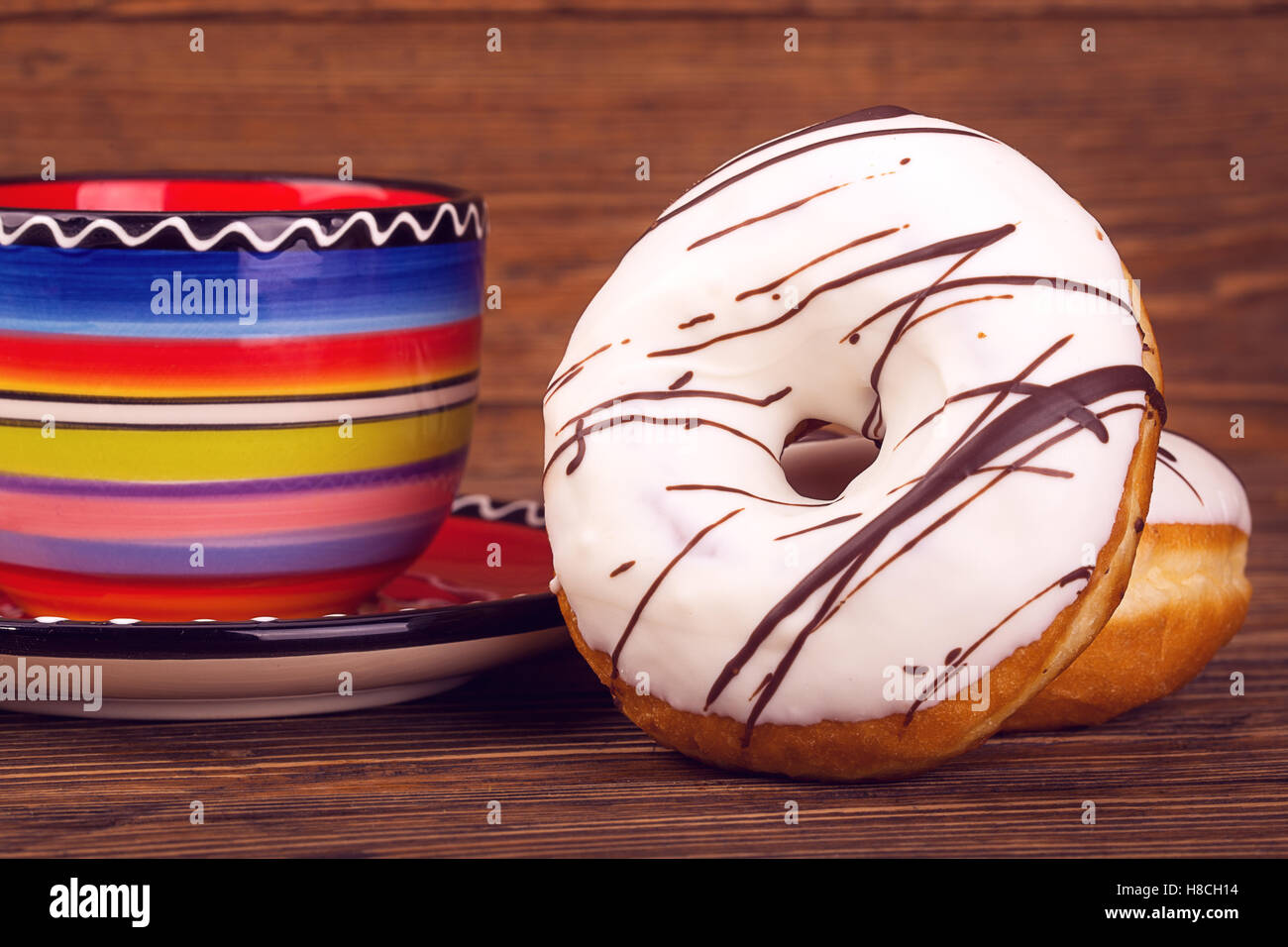 Two donuts on the background beautiful bright color (blue, red, pink, yellow) circle on saucer on vintage wooden table Stock Photo