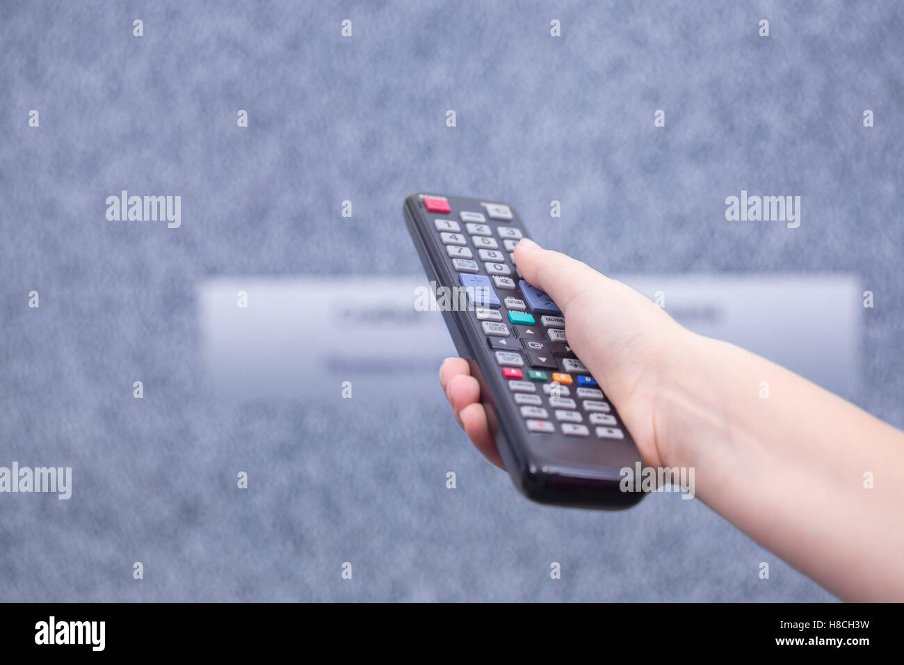 It does not show on the TV channel. Hand using a remote to change channel. Selective focus on the thumb. Stock Photo