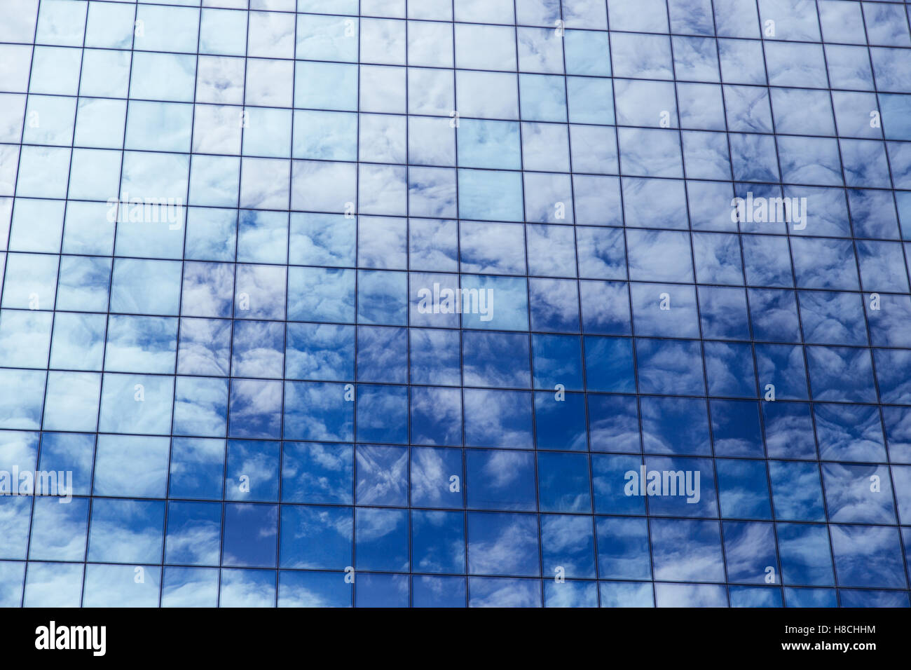 Clouds reflected in windows of modern office building against the blue ...