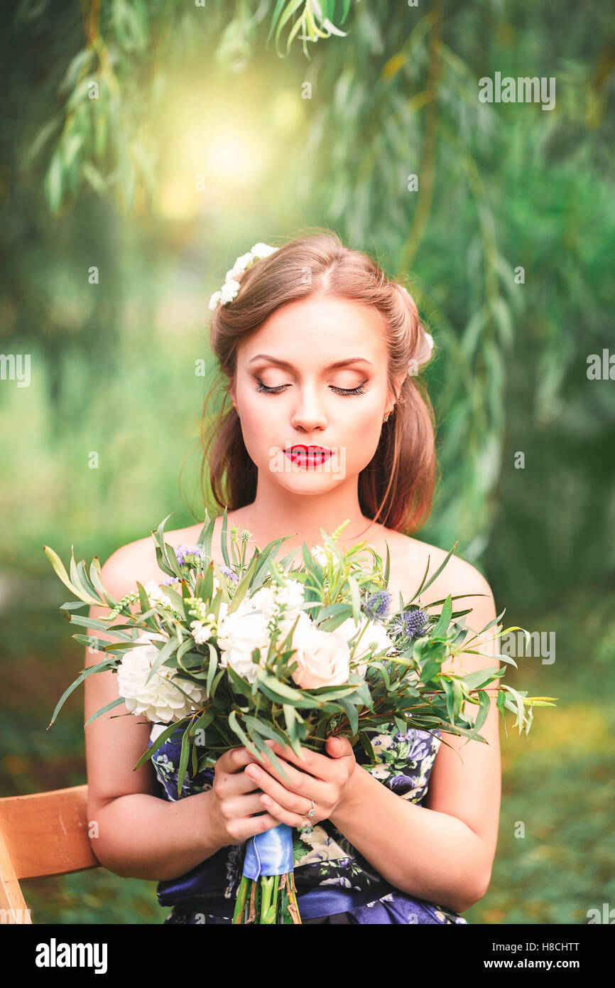 beautiful young woman with a bouquet of flowers in their hands outdoor ...