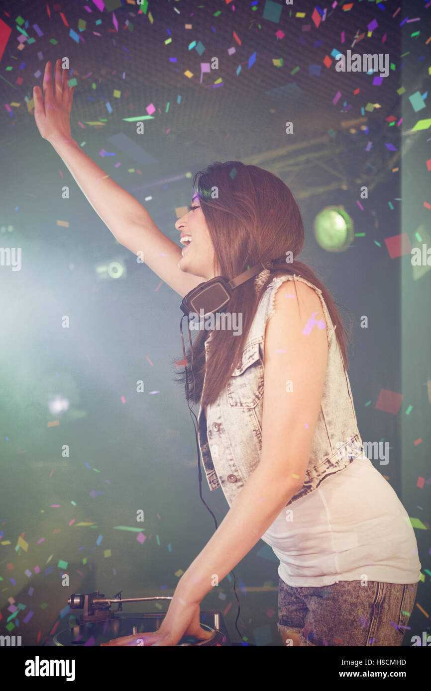 Composite image of side view of pretty female dj waving her hand while playing music Stock Photo