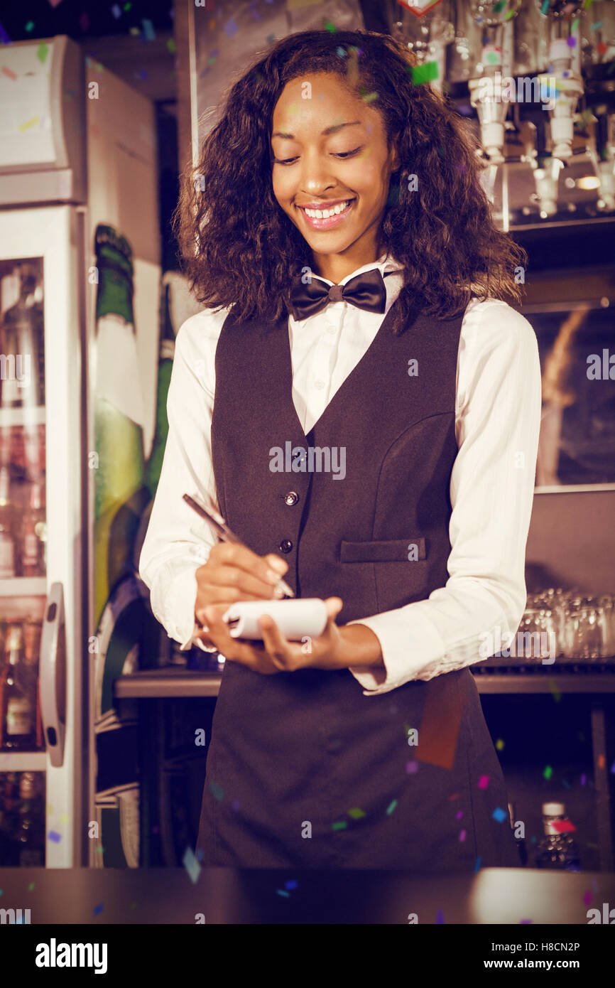 Composite image of cheerful bartender writing down order Stock Photo