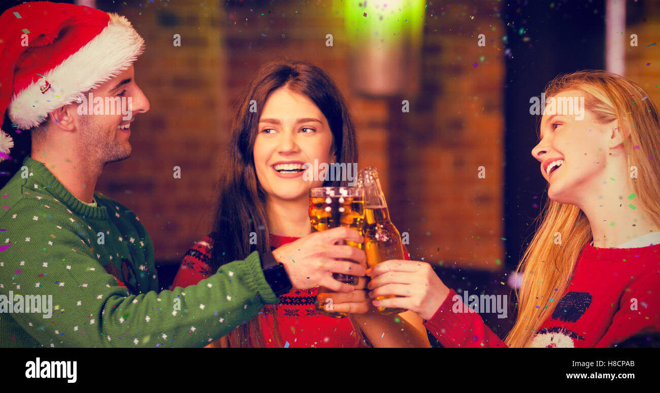 Composite image of cheerful friends having drinks during christmas Stock Photo