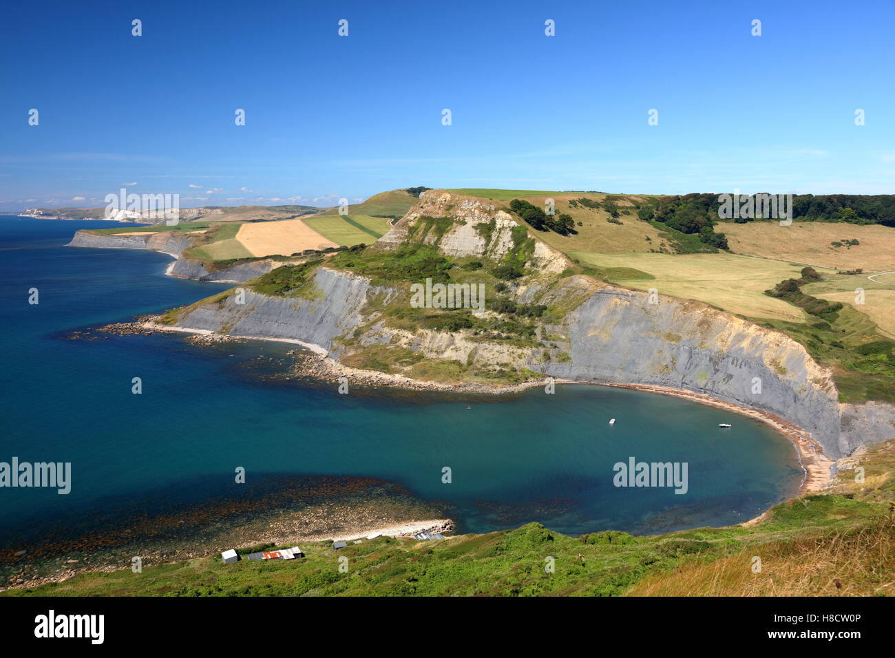 Chapman's Pool Dorset UK with fishermans huts, Houns Tout and Jurassic coastline sweeping away towards Weymouth and blue sky Stock Photo