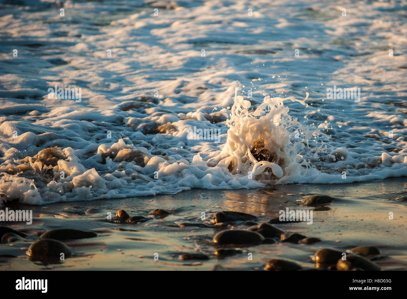 Sea water rushing over the shoreline rocks Stock Photo