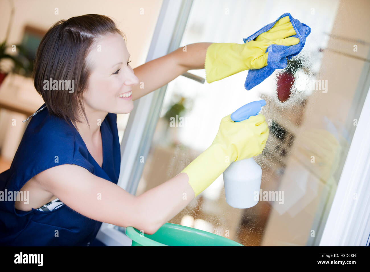 Young charwoman cleaning the window Stock Photo