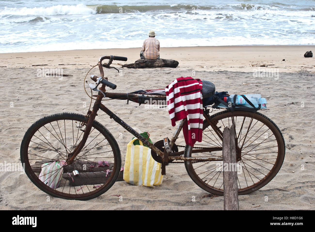 Back view of a lonely old man fishing in the Indian ocean. In the foreground, his bicycle ( Madagascar). Stock Photo