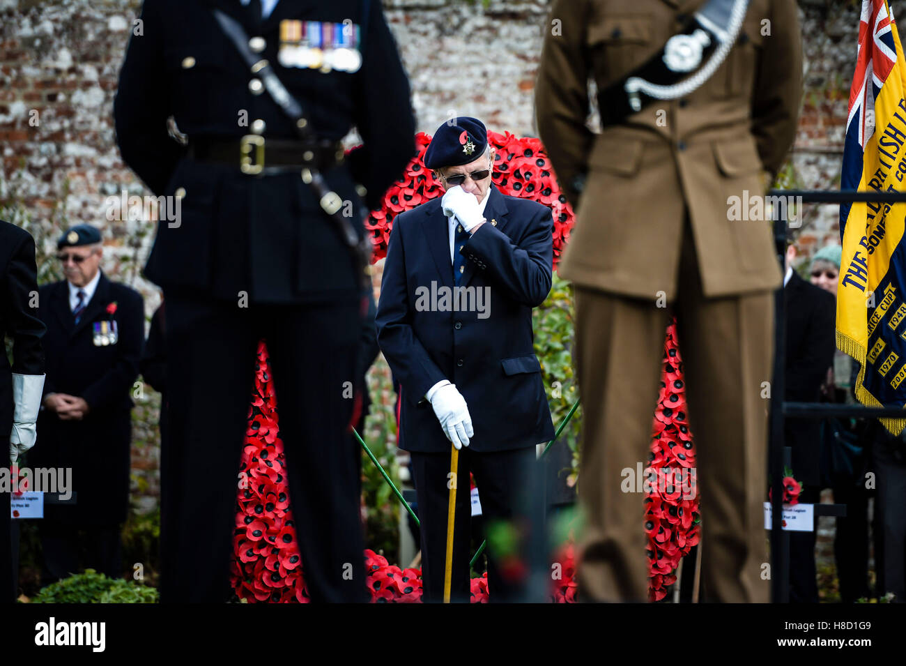 A Royal British Legion standard bearer leader wipes his eyes after