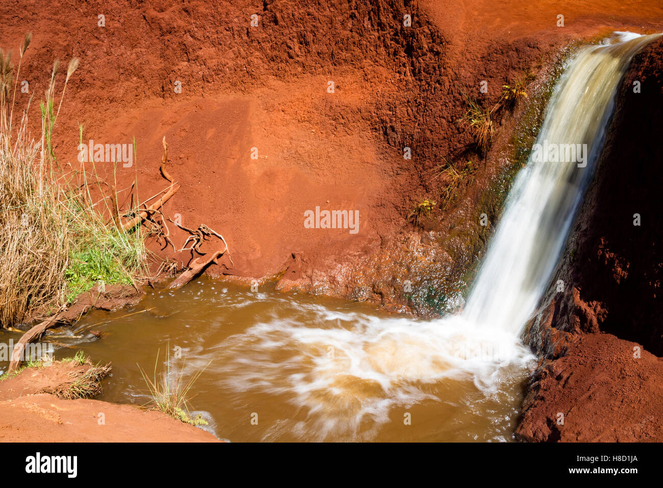A small waterfall digging through red soil in the Waimea Canyon on Kauai, Hawaii, USA. Stock Photo