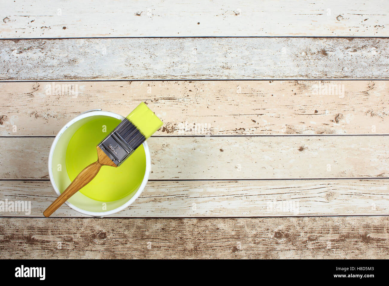 Loaded paintbrush placed across a white paint kettle filled with lime