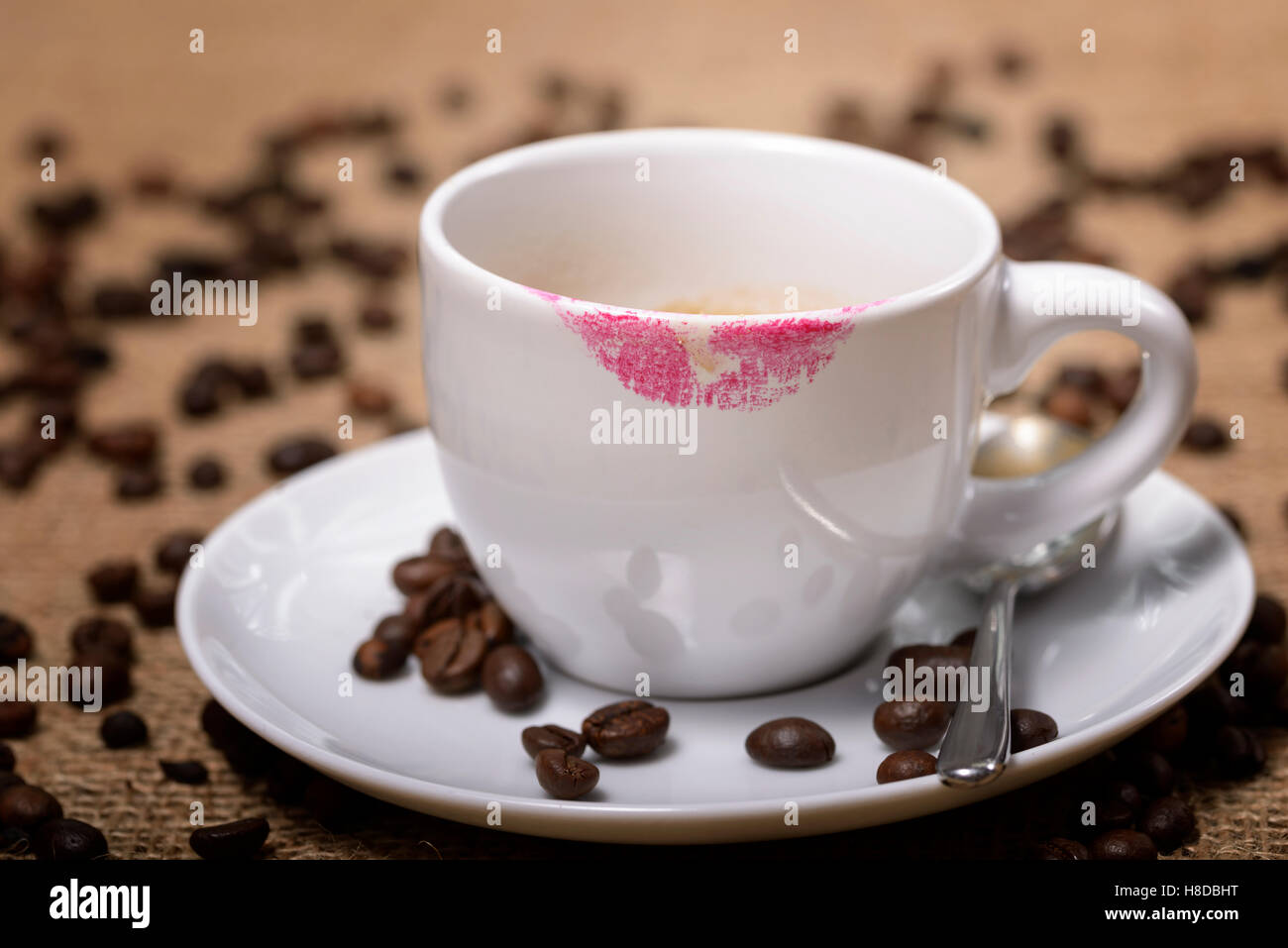 cup of coffee with lipstick traces and coffee beans around Stock Photo