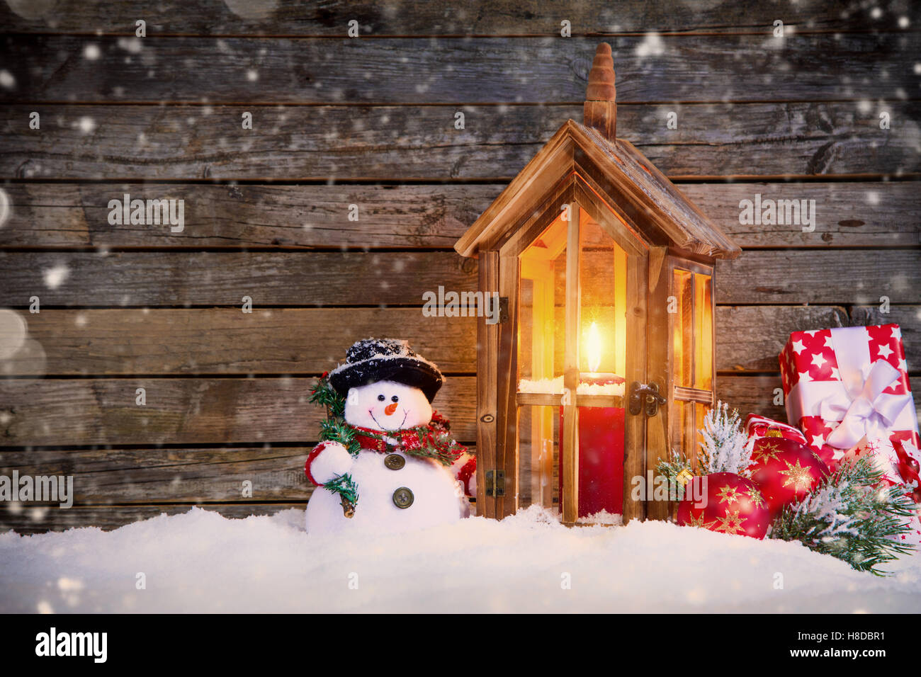 Christmas background with snowman and wooden lantern in snow. Copyspace for text Stock Photo