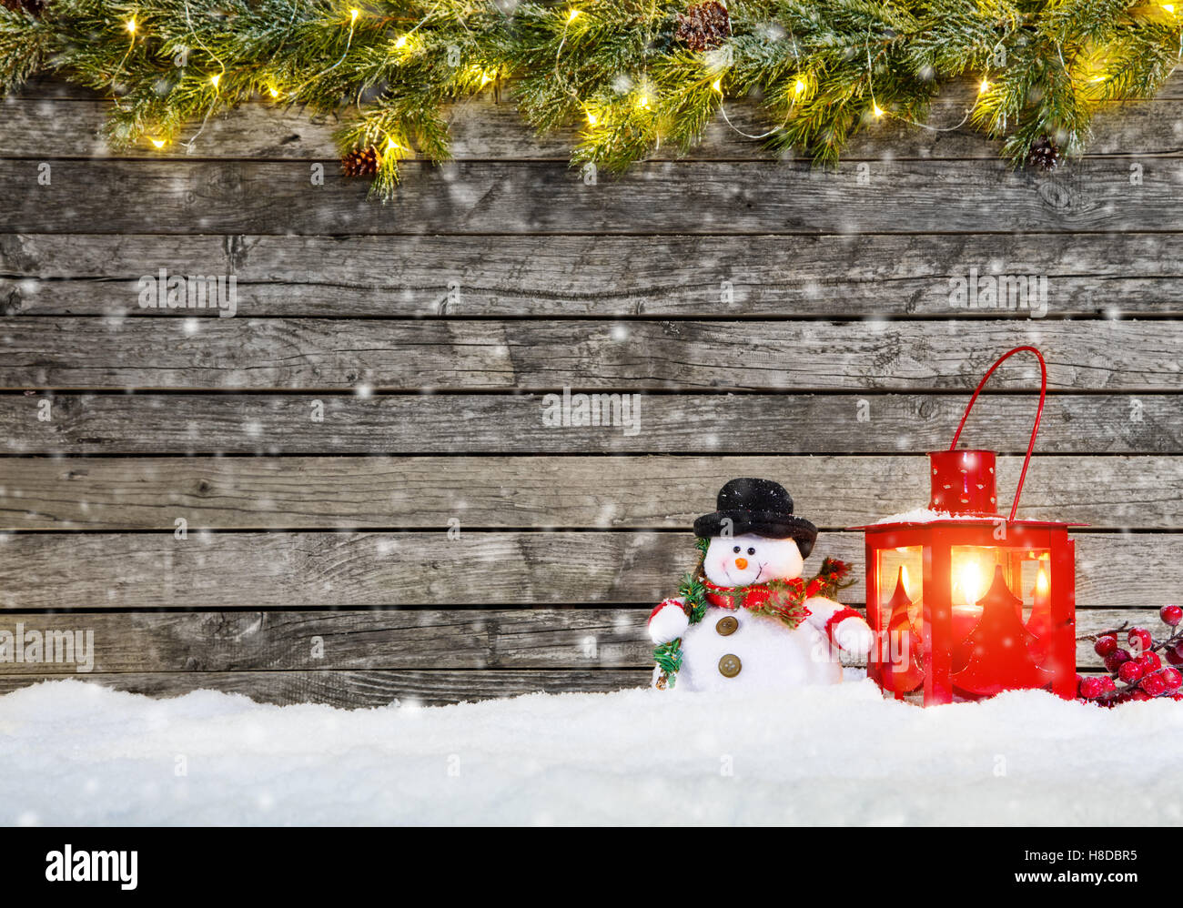 Christmas background with snowman and red lantern in snow. Fir decoration branches on top Stock Photo