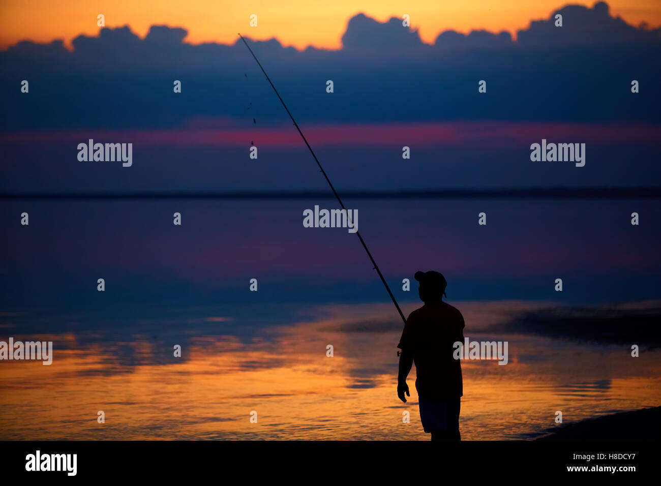 Silhouette of fishermen on quiet ocean with rays sunset Stock Photo - Alamy