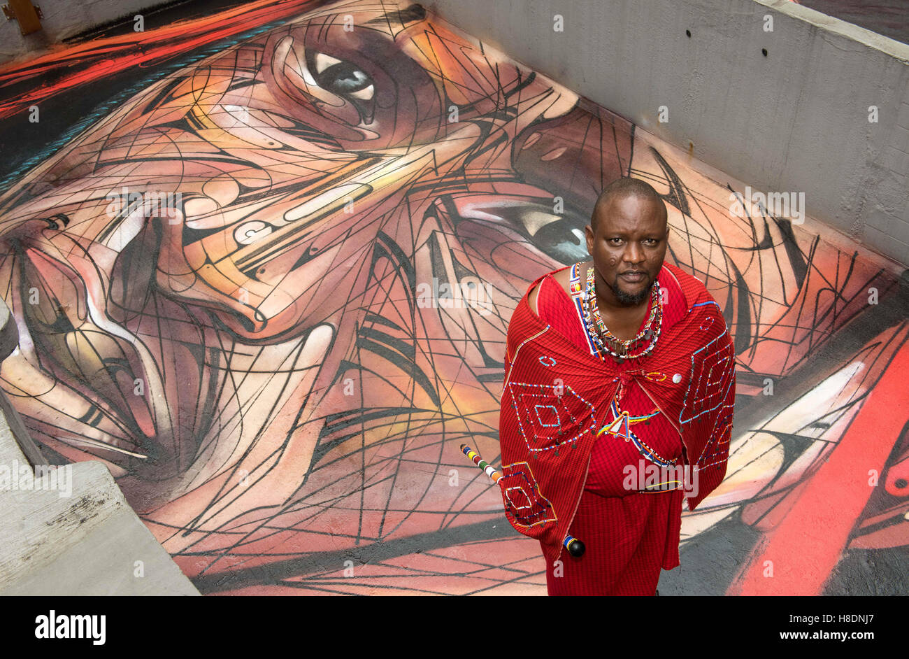 Hong Kong, Hong Kong S.A.R, China. 10th Nov, 2016. Masai warrior and representative of the Big Life foundation in Kenya, Daniel Ole Sambu, with the rooftop painting of himself painted by famous Parisian street artist Alexandre Monteiro aka Hopare.Street art in Hong Kong ahead of the The 'Hope for Wildlife' Gala Dinner painted to raise awareness for the plight of endangered animals the world over.10th November 2016. Photo by Jayne Russell. © Jayne Russell/ZUMA Wire/Alamy Live News Stock Photo
