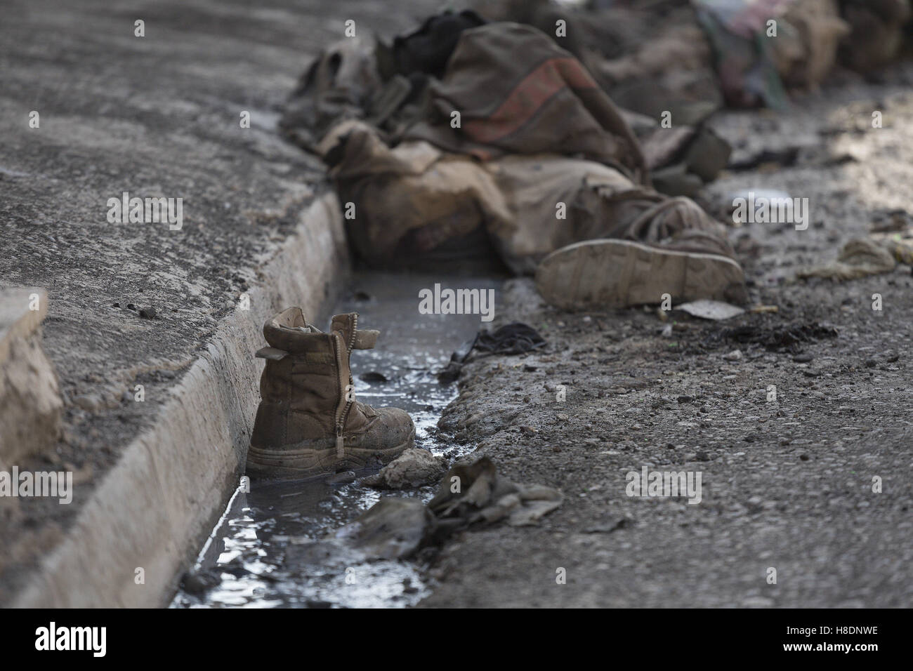 Mosul, Nineveh, Iraq. 11th Nov, 2016. 11/11/2016. Mosul, Iraq. A boot sits in a gutter and beyond the dead bodies of ISIS extremists, killed four days before by Iraqi forces, are seen in Mosul's Al Intisar district on the south east of the city. The Al Intisar district was taken four days ago by Iraqi Security Forces (ISF) and, despite its proximity to ongoing fighting between ISF and ISIS militants, many residents still live in the settlement without regular power and water and with dwindling food supplies. Credit:  ZUMA Press, Inc./Alamy Live News Stock Photo