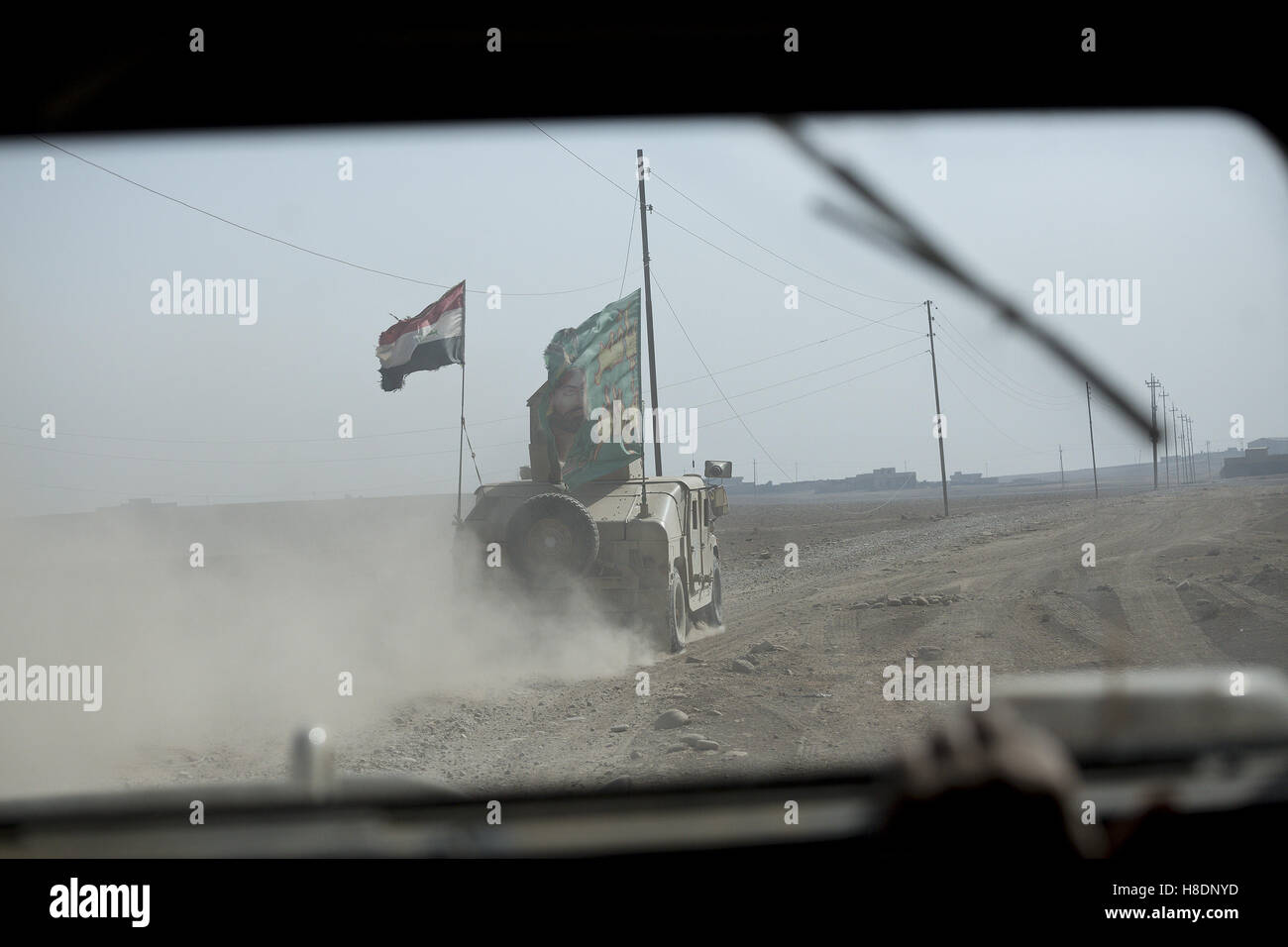 Mosul, Nineveh, Iraq. 11th Nov, 2016. 11/11/2016. Mosul, Iraq. Seen through an armoured windscreen an Iraqi Army armoured Humvee, flying Shia and Iraqi national flags and belonging to the Iraqi Army's 9th Armoured Division, drives along a track on the outskirts of Mosul, Iraq. Credit:  ZUMA Press, Inc./Alamy Live News Stock Photo