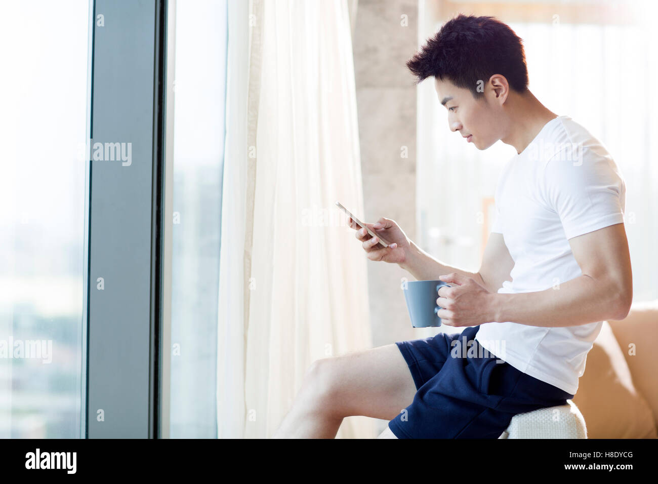 Young Chinese man using smart phone at home Stock Photo