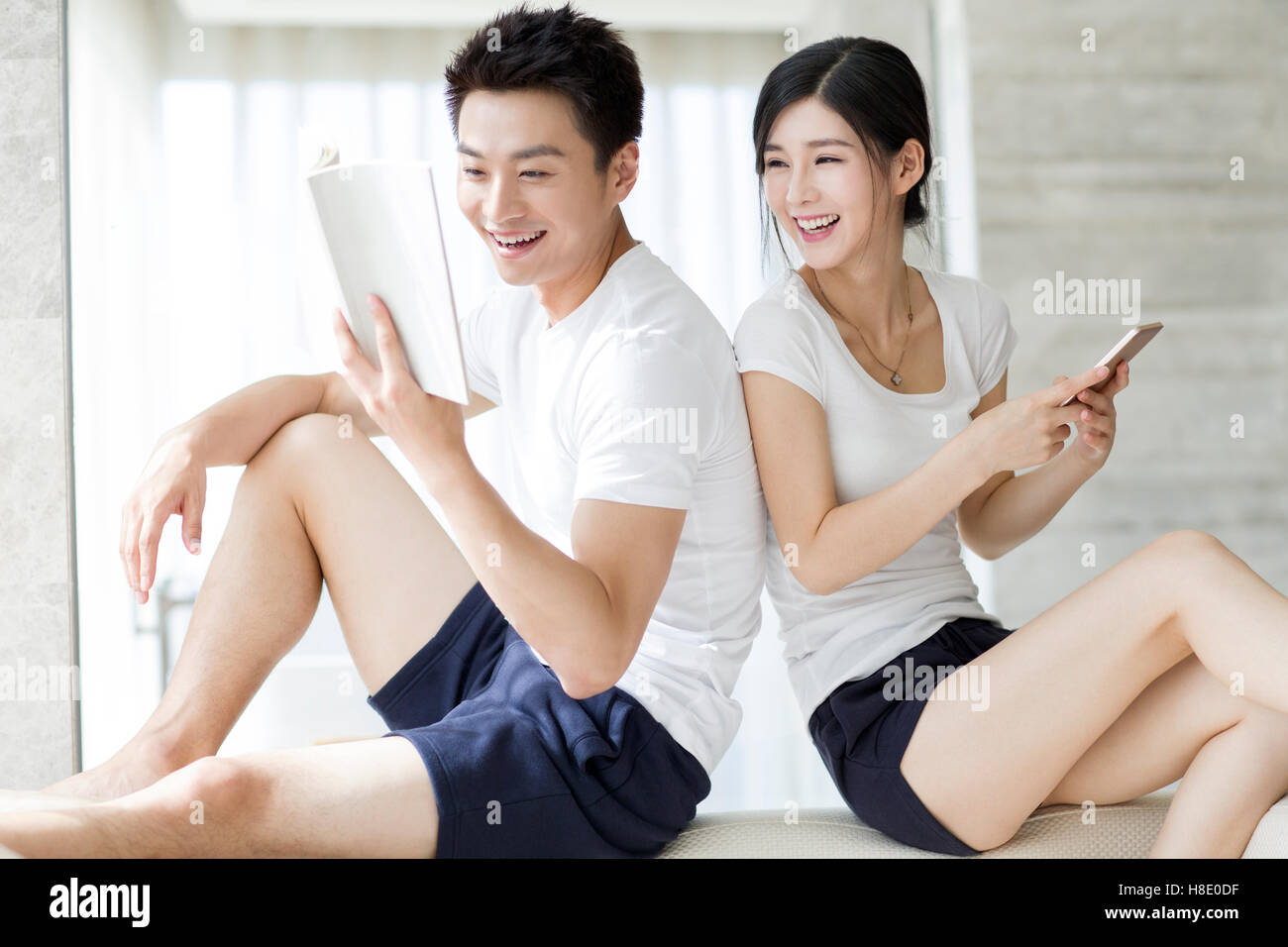 Happy young Chinese couple relaxing at home Stock Photo - Alamy