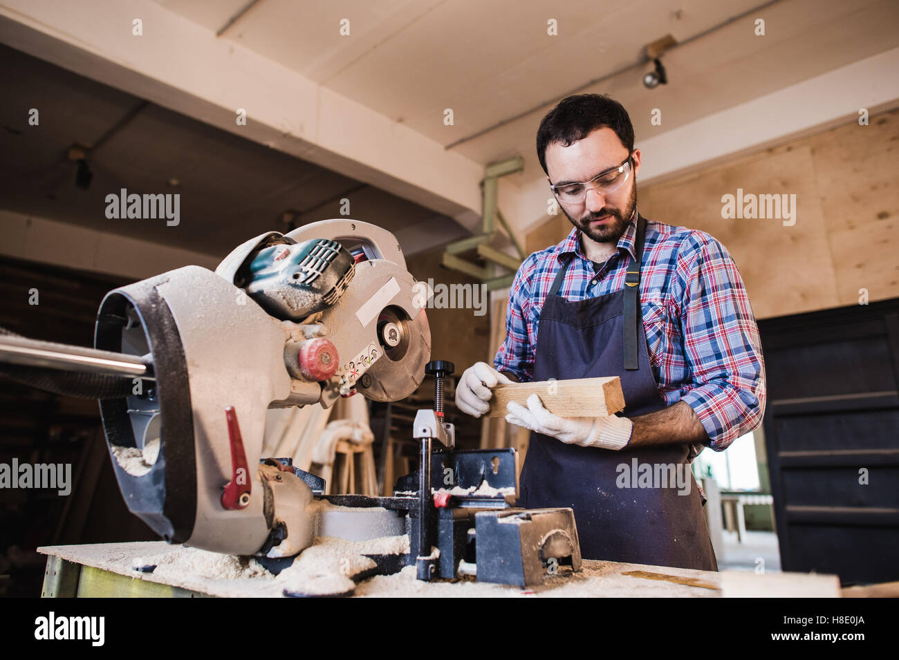 Carpenter working on an electric buzz saw cutting some boards, he is ...