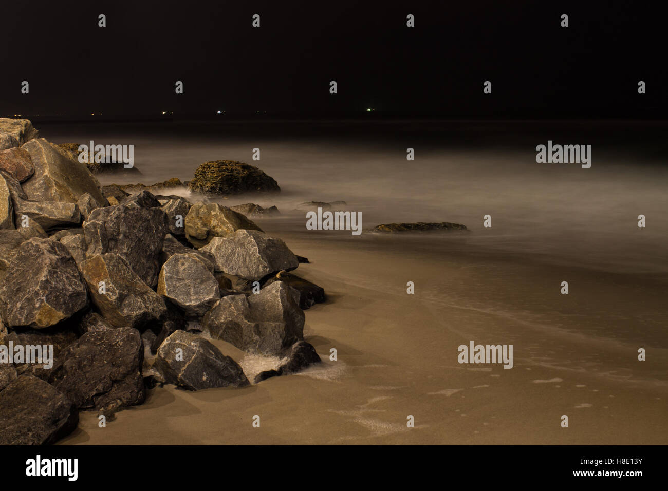 Coastal ocean rocks in a dark with black night sky and fog.Long ...