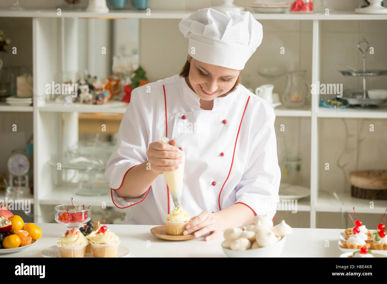 Portrait of confectioner topping a cupcake with cream Stock Photo