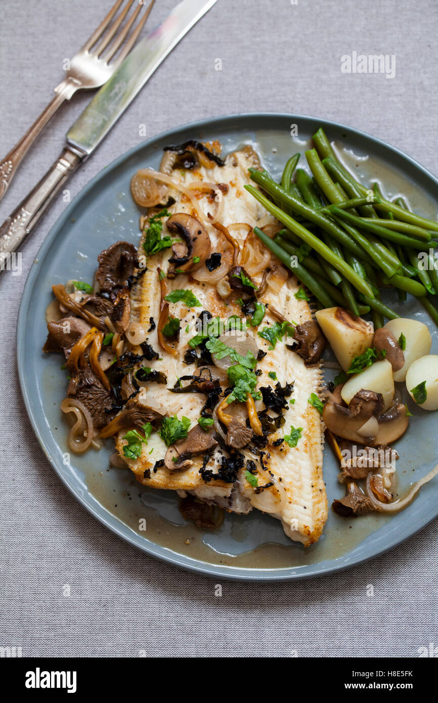 Hot soused Dover sole with wild mushrooms, shallots and seaweed flakes with green beans and potatoes Stock Photo