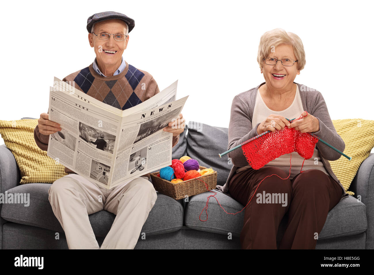 Mature man holding a newspaper and a mature woman knitting sitting on a ...