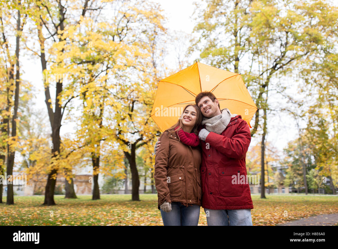 smiling couple with umbrella in autumn park Stock Photo - Alamy