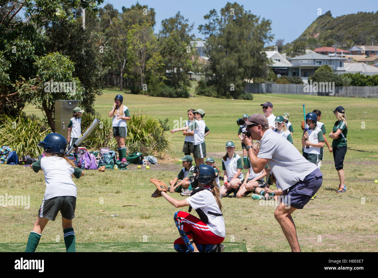 Australian girls school children play each other at softball soft ball on a Sydney park area,Australia Stock Photo