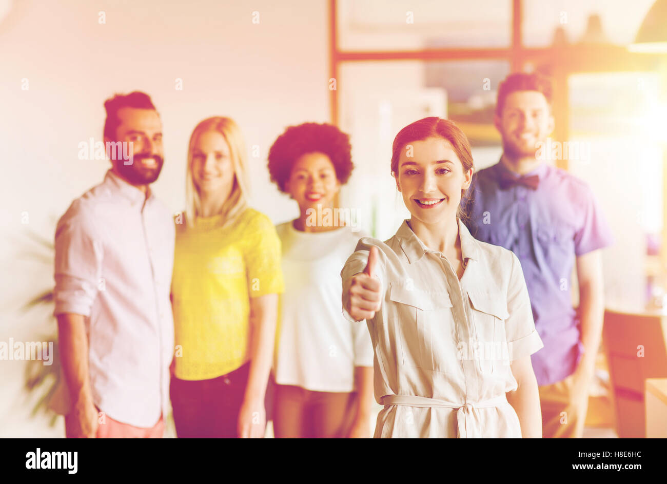woman showing thumbs up over creative office team Stock Photo - Alamy