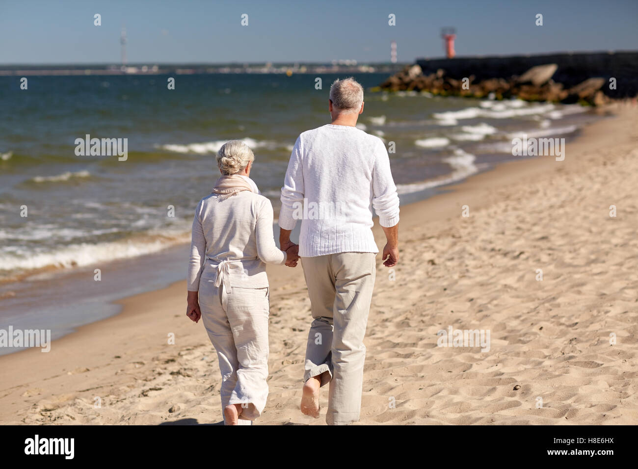 Old couple walking along beach hi-res stock photography and images - Alamy