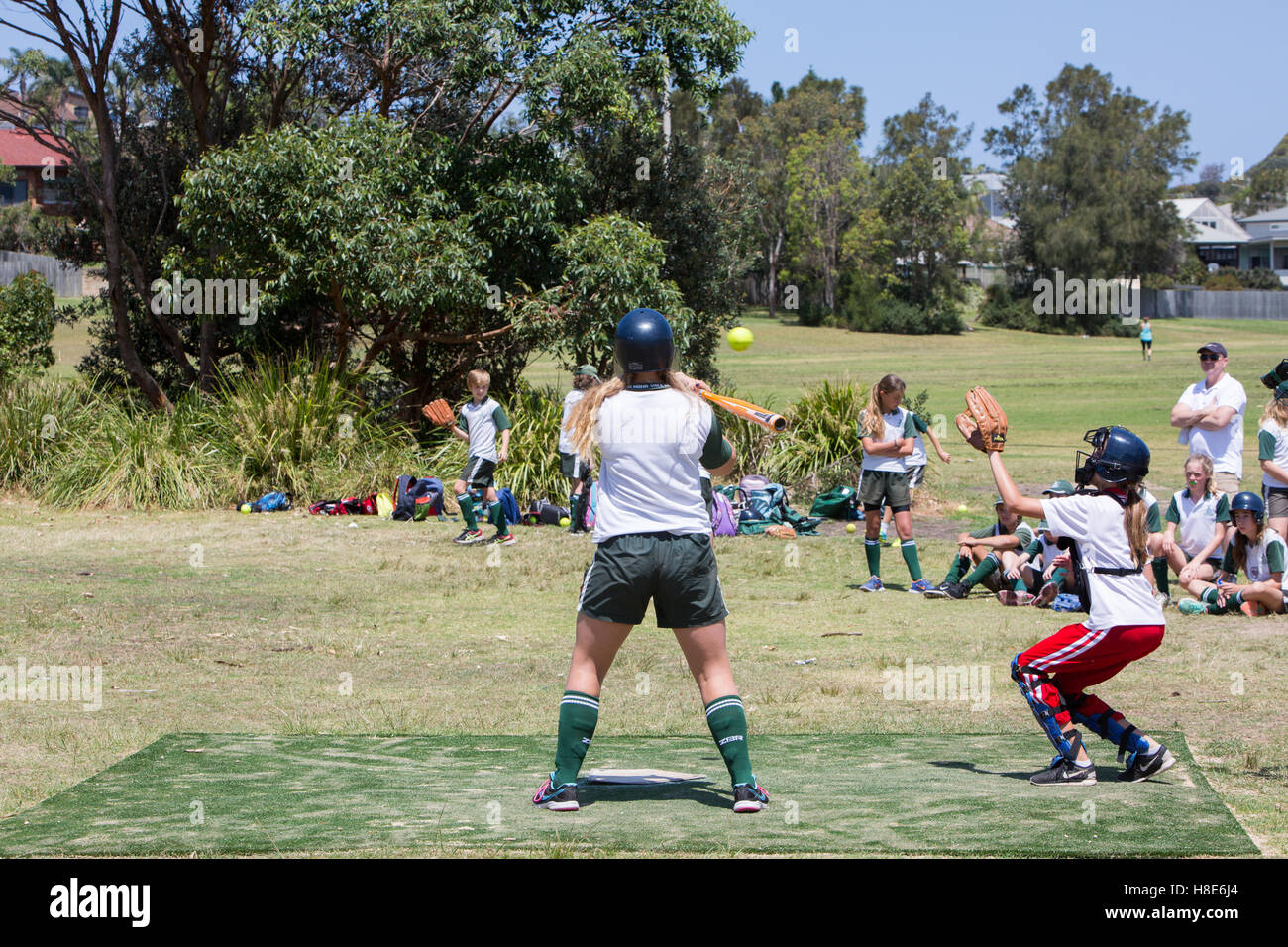 Australian girls school children play each other at softball soft ball on a Sydney park area,Australia Stock Photo