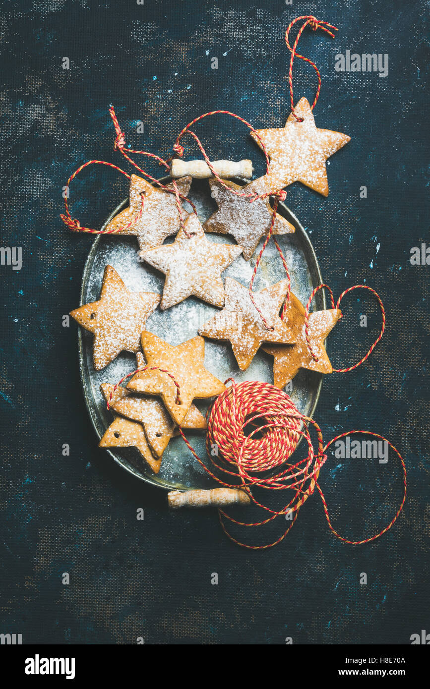 Christmas holiday star shaped gingerbread cookies for Christmas tree decoration with red ropes in vintage metal tray over dark b Stock Photo