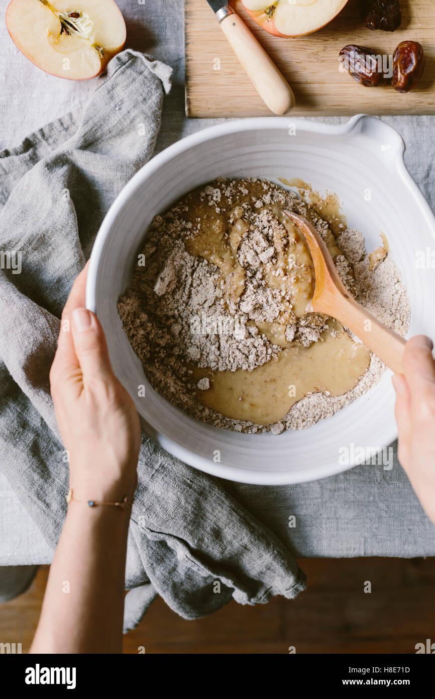 A woman is photographed as she is folding dry ingredients in to wet