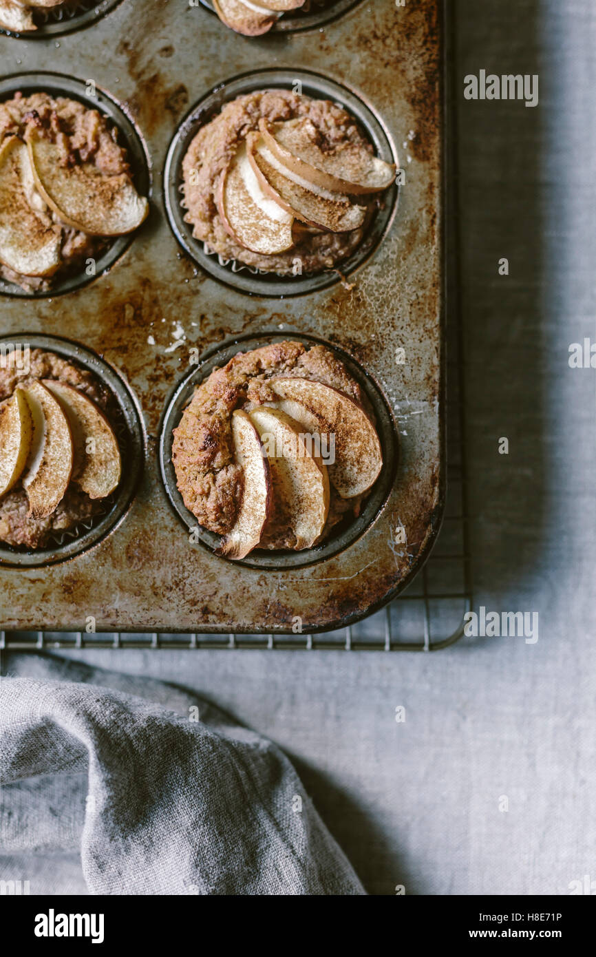 Freshly baked apple muffins that are still in the muffin tin are photographed from the top view. Stock Photo