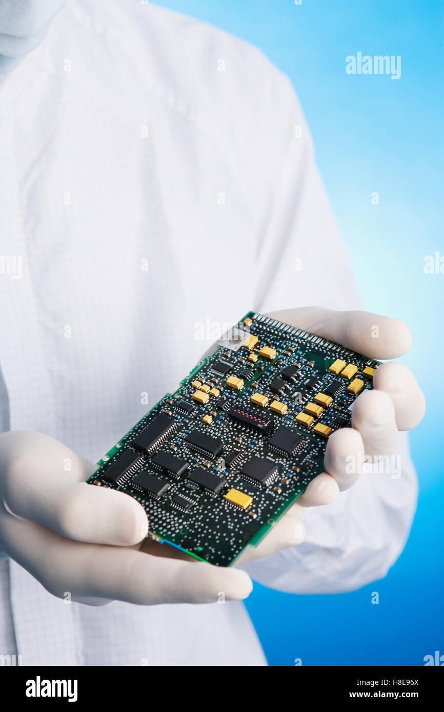 Man in a clean-room suit holding a computer circuit board Stock Photo ...
