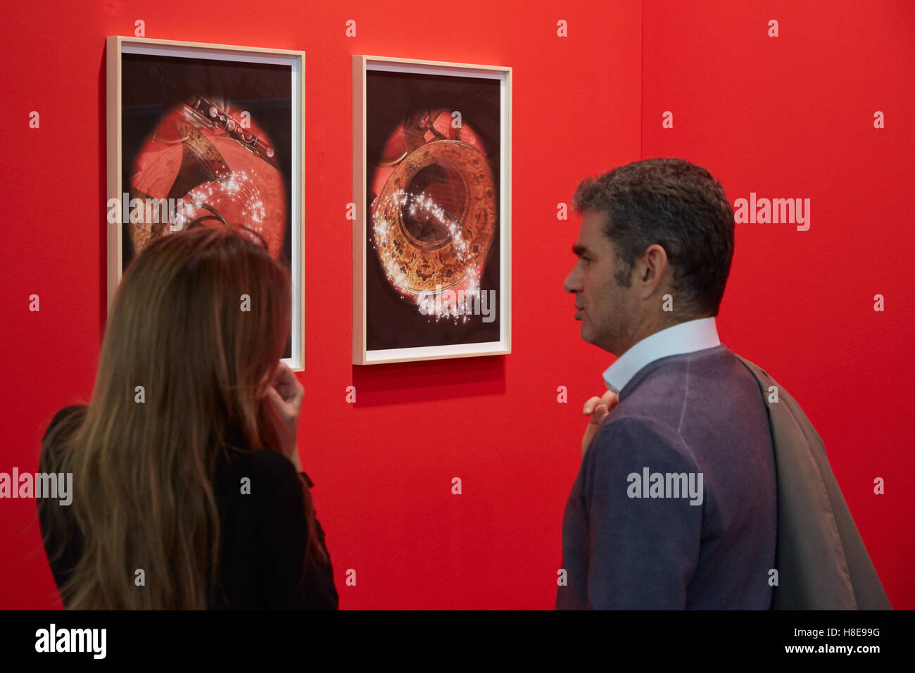 Woman and man looking at pictures on red wall during Artissima, contemporary art fair opening Stock Photo